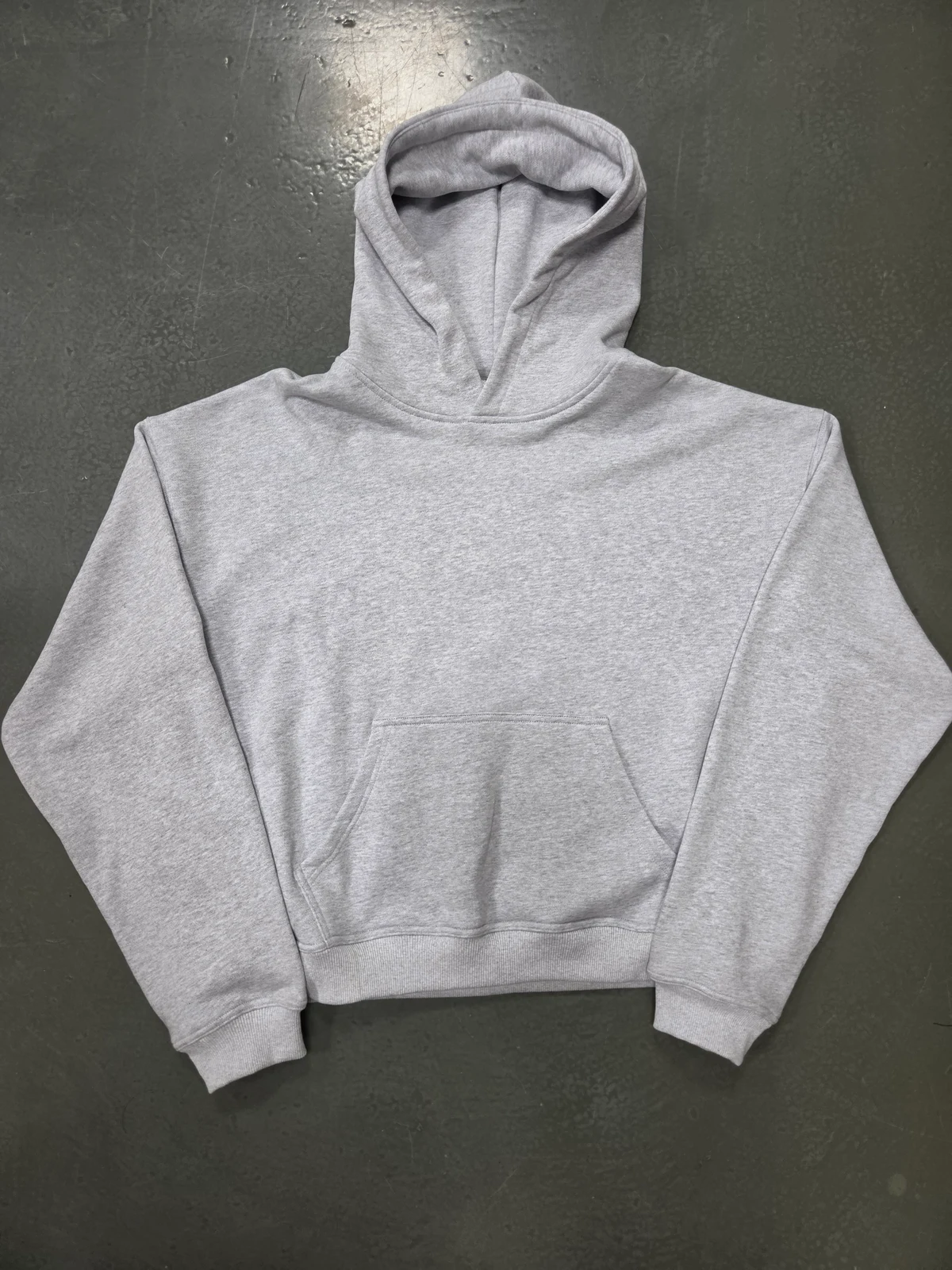 Actual grey pullover hoodie sample with a kangaroo pocket and ribbed hem