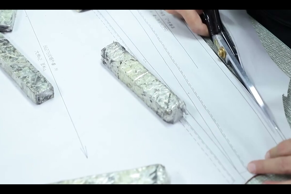 Factory worker cutting pattern paper on table